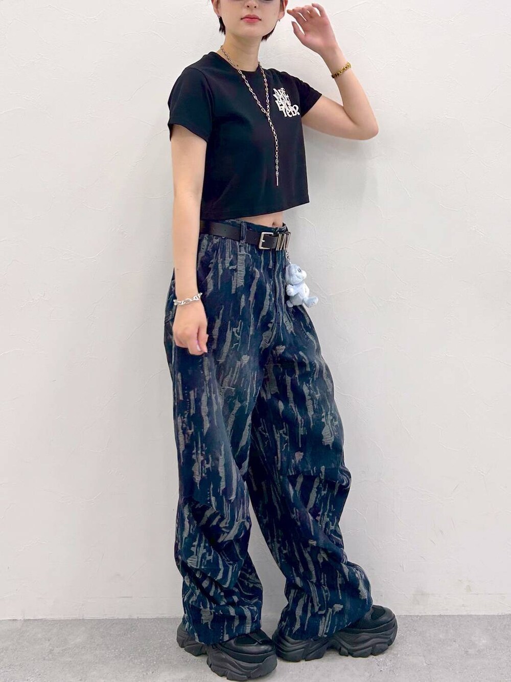 ブラック系のスニーカー、ブラック系のTシャツ/カットソー、ブルー系のデニムパンツを着用したレディースの夏コーディネートの7枚目の写真