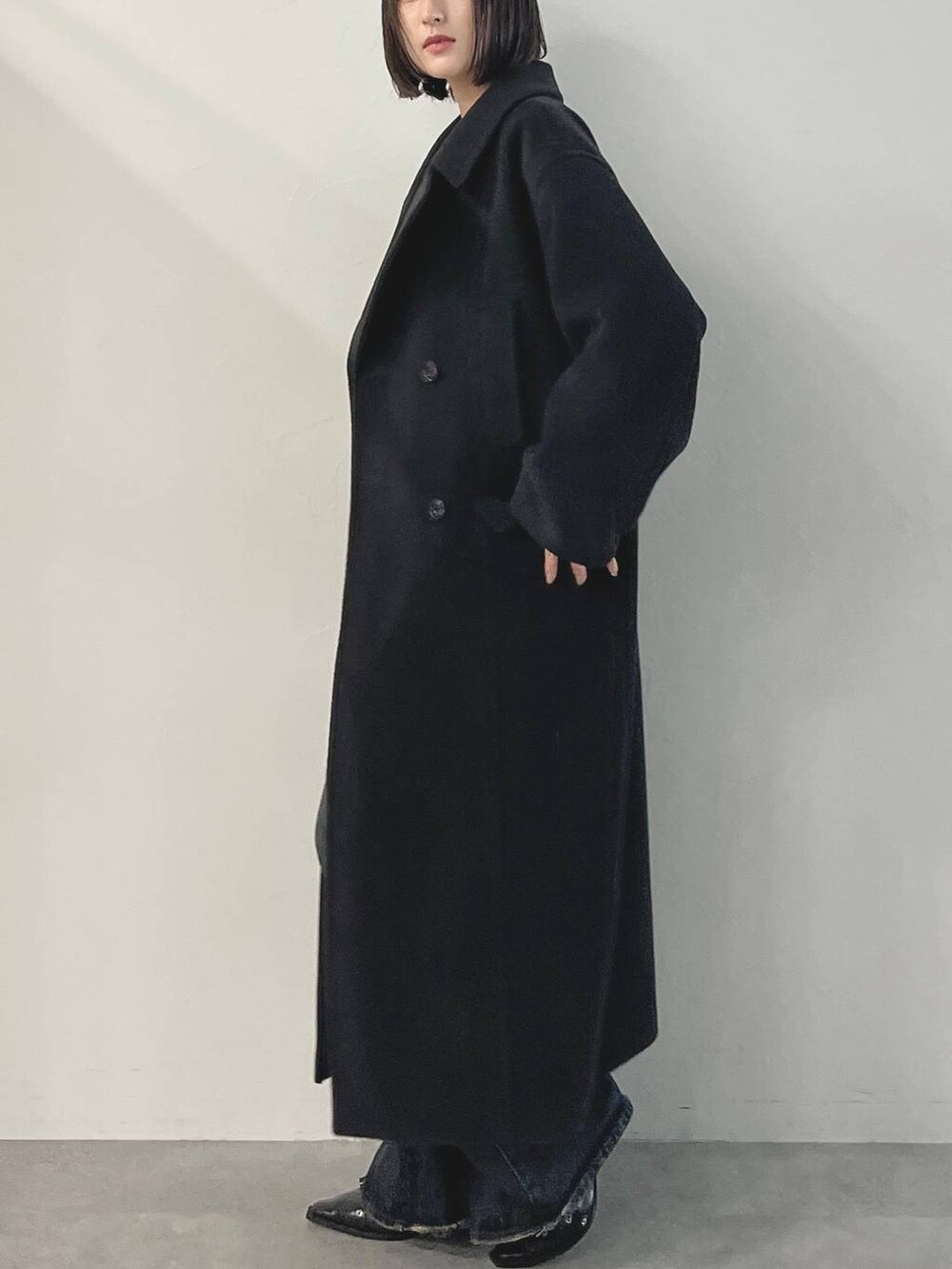 ブルー系のデニムパンツ、ブラック系のパンプス、ブラック系のチェスターコートを着用したレディースの秋コーディネートの6枚目の写真