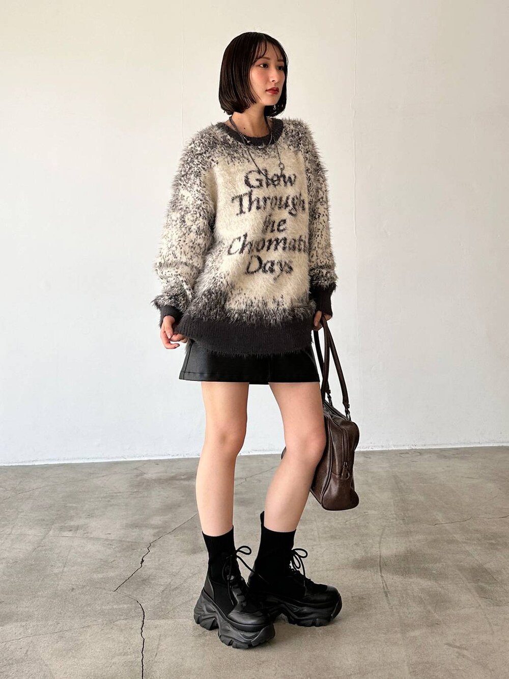 ブラック系のブーツ、ブラウン系のボストンバッグ、グレー系のニット/セーターを着用したレディースの秋コーディネートの5枚目の写真