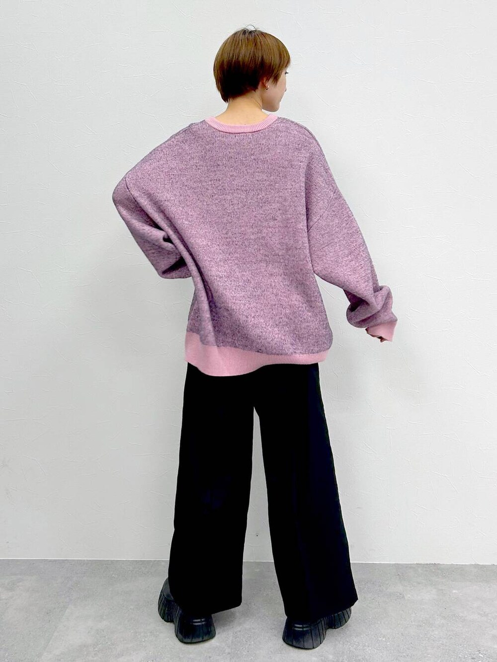 ピンク系のニット/セーター、ブラック系のブーツ、ブラック系のスラックスを着用したレディースの冬コーディネートの7枚目の写真