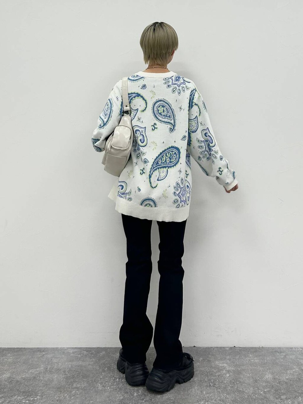 ブラック系のスニーカー、ホワイト系のショルダーバッグ、ブラック系のデニムパンツを着用したレディースの冬コーディネートの7枚目の写真