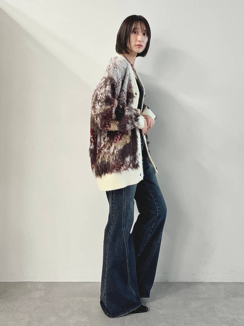 ブルー系のデニムパンツ、ブラック系のパンプス、ホワイト系のカーディガン/ボレロを着用したレディースの秋コーディネートの7枚目の写真