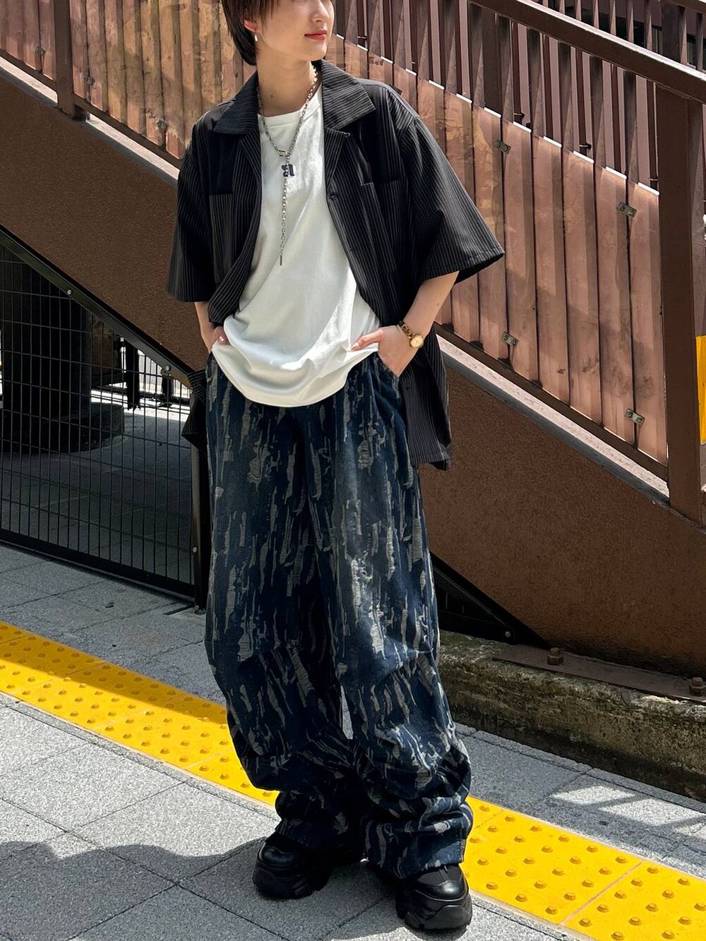 ブラック系のスニーカー、ホワイト系のTシャツ/カットソー、ブラック系のシャツ/ブラウスを着用したレディースの秋コーディネートの2枚目の写真