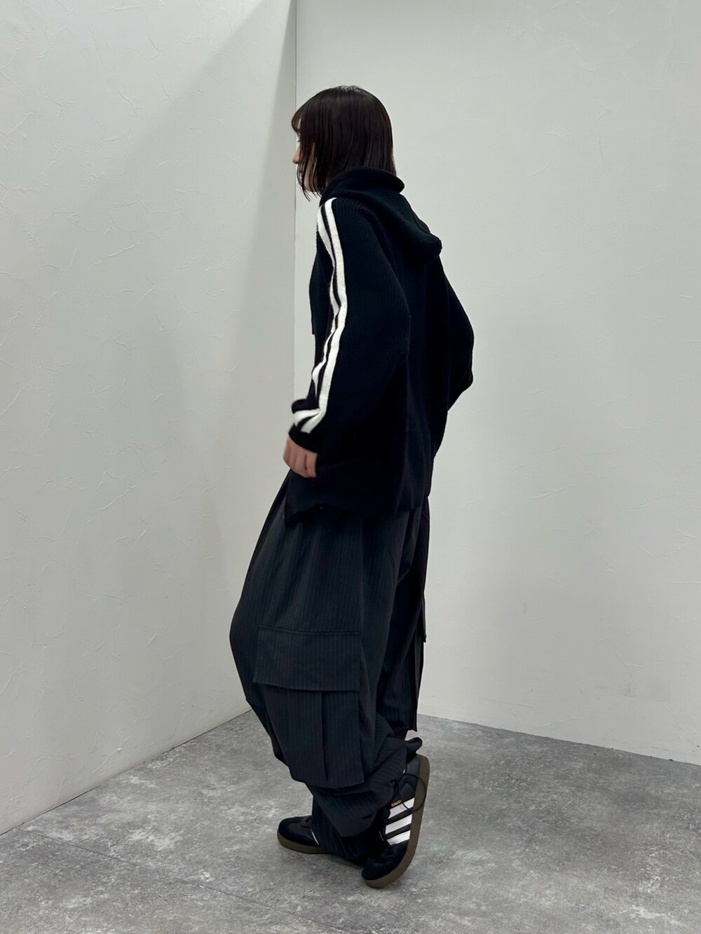 ブラック系のスニーカー、ブラック系のニット/セーター、ブラック系のカーゴパンツを着用したレディースの秋コーディネートの3枚目の写真