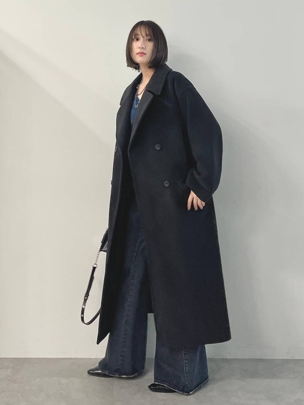 ブルー系のデニムパンツ、ブラック系のパンプス、ブラック系のチェスターコートを着用したレディースの秋コーディネートの5枚目の写真