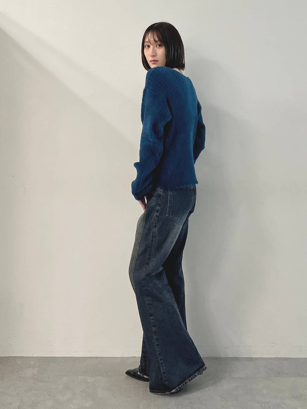 ブルー系のデニムパンツ、ブラック系のパンプス、グリーン系のニット/セーターを着用したレディースの秋コーディネートの3枚目の写真