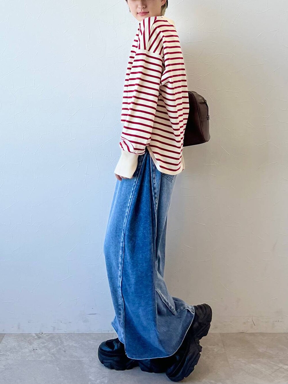 ブラック系のスニーカー、ブラウン系のボストンバッグ、ブルー系のデニムパンツを着用したレディースの春コーディネートの5枚目の写真