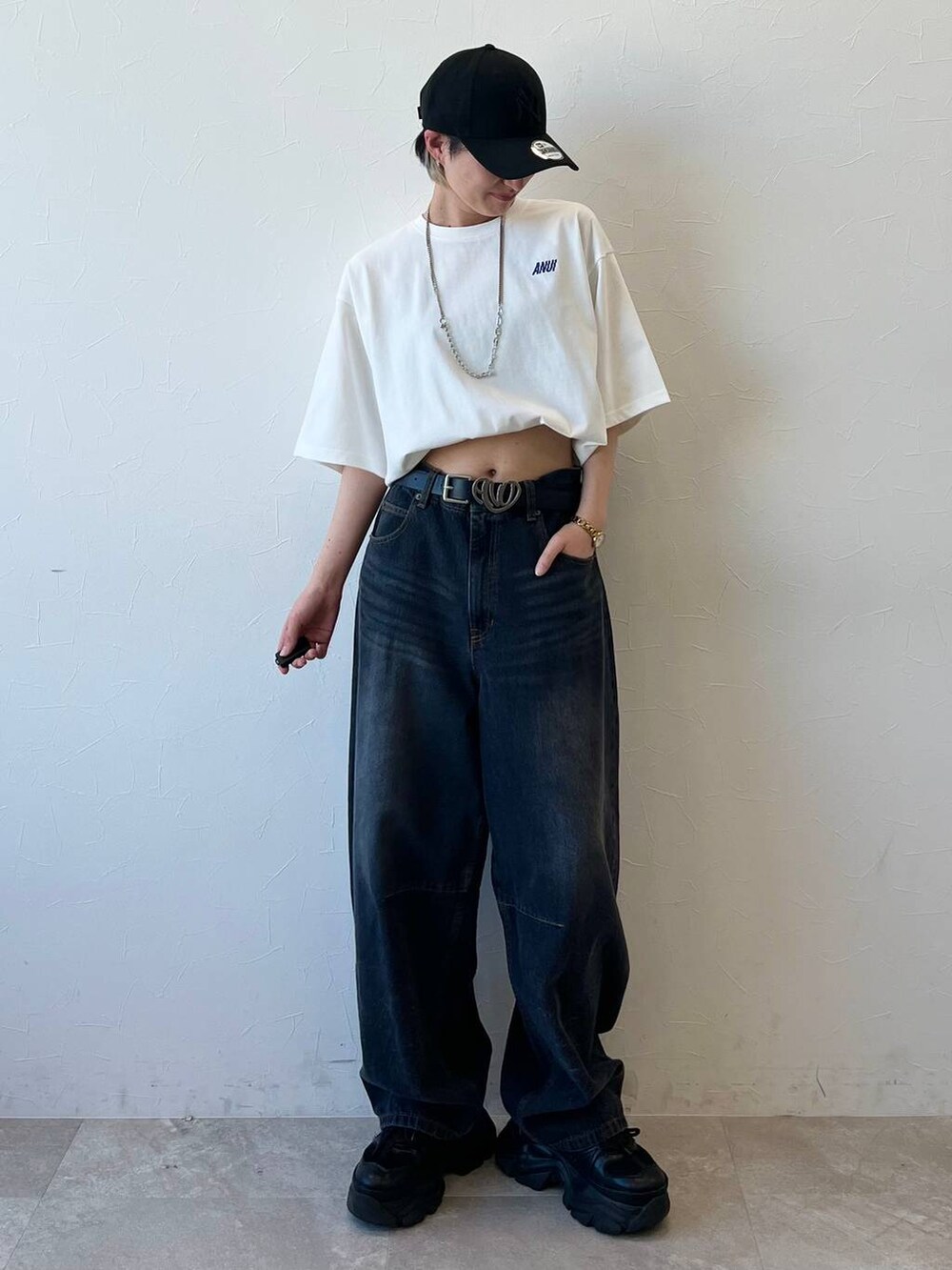 ブラック系のスニーカー、ブラック系のデニムパンツ、ホワイト系のTシャツ/カットソーを着用したレディースの春コーディネートの3枚目の写真