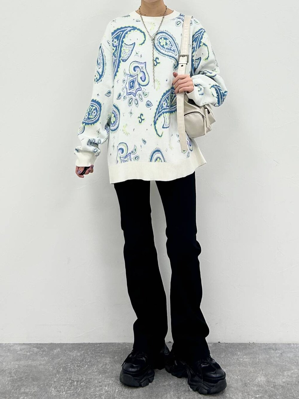 ブラック系のスニーカー、ホワイト系のショルダーバッグ、ブラック系のデニムパンツを着用したレディースの冬コーディネートの2枚目の写真