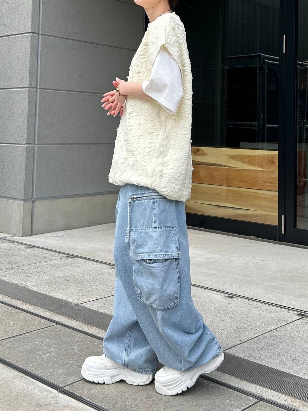 ホワイト系のベスト、ホワイト系のTシャツ/カットソー、ブルー系のデニムパンツを着用したレディースの夏コーディネートの4枚目の写真