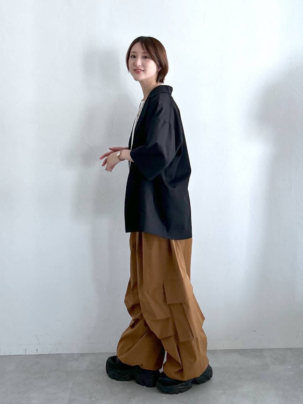 ブラック系のテーラードジャケット、ブラウン系のカーゴパンツ、ホワイト系のTシャツ/カットソーを着用したレディースの春コーディネートの6枚目の写真
