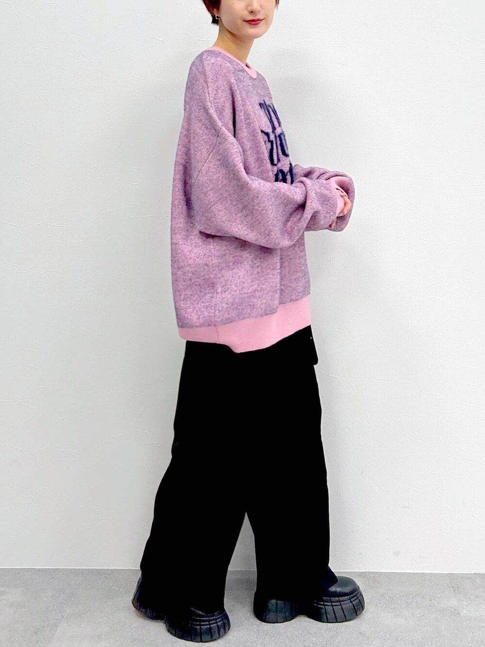 ピンク系のニット/セーター、ブラック系のブーツ、ブラック系のスラックスを着用したレディースの冬コーディネートの6枚目の写真