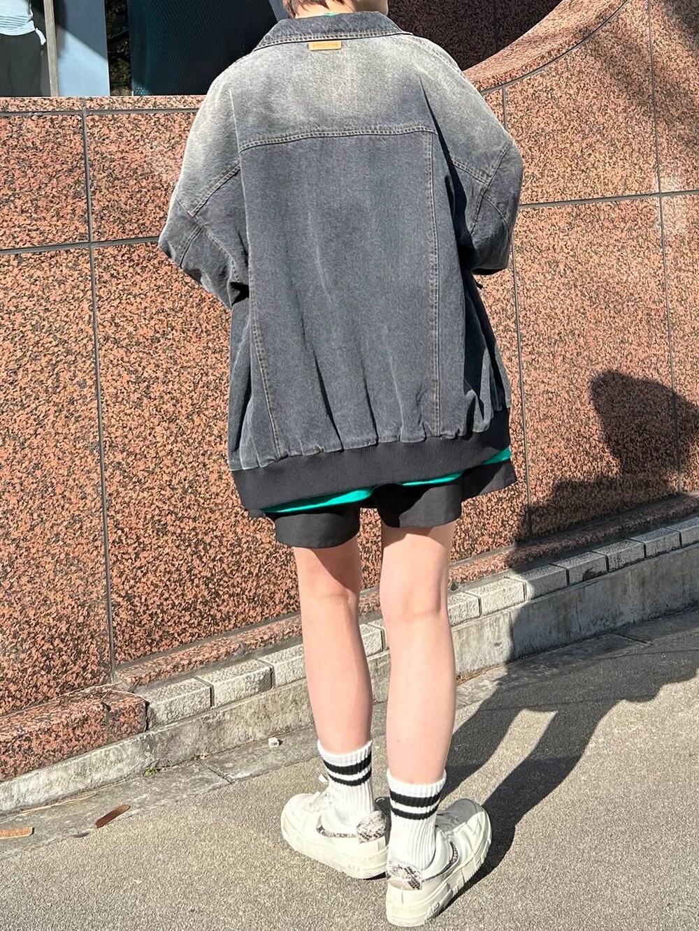 ブラック系のデニムジャケット、グリーン系のTシャツ/カットソー、ブラック系のキャップを着用したレディースの春コーディネートの5枚目の写真