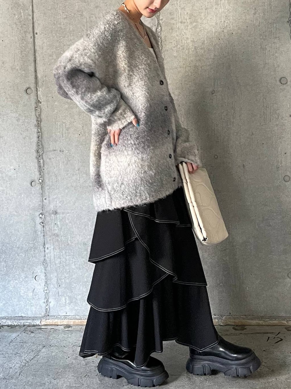 ホワイト系のキャミソール、ブラック系のブーツ、ホワイト系のクラッチバッグを着用したレディースの冬コーディネートの7枚目の写真