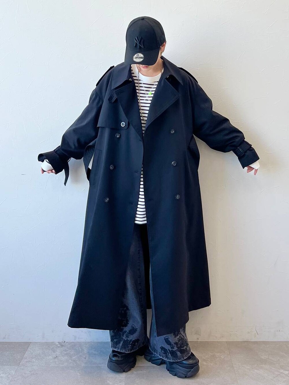 ブラック系のスニーカー、ブラック系のトレンチコート、ブラック系のデニムパンツを着用したレディースの春コーディネートの2枚目の写真