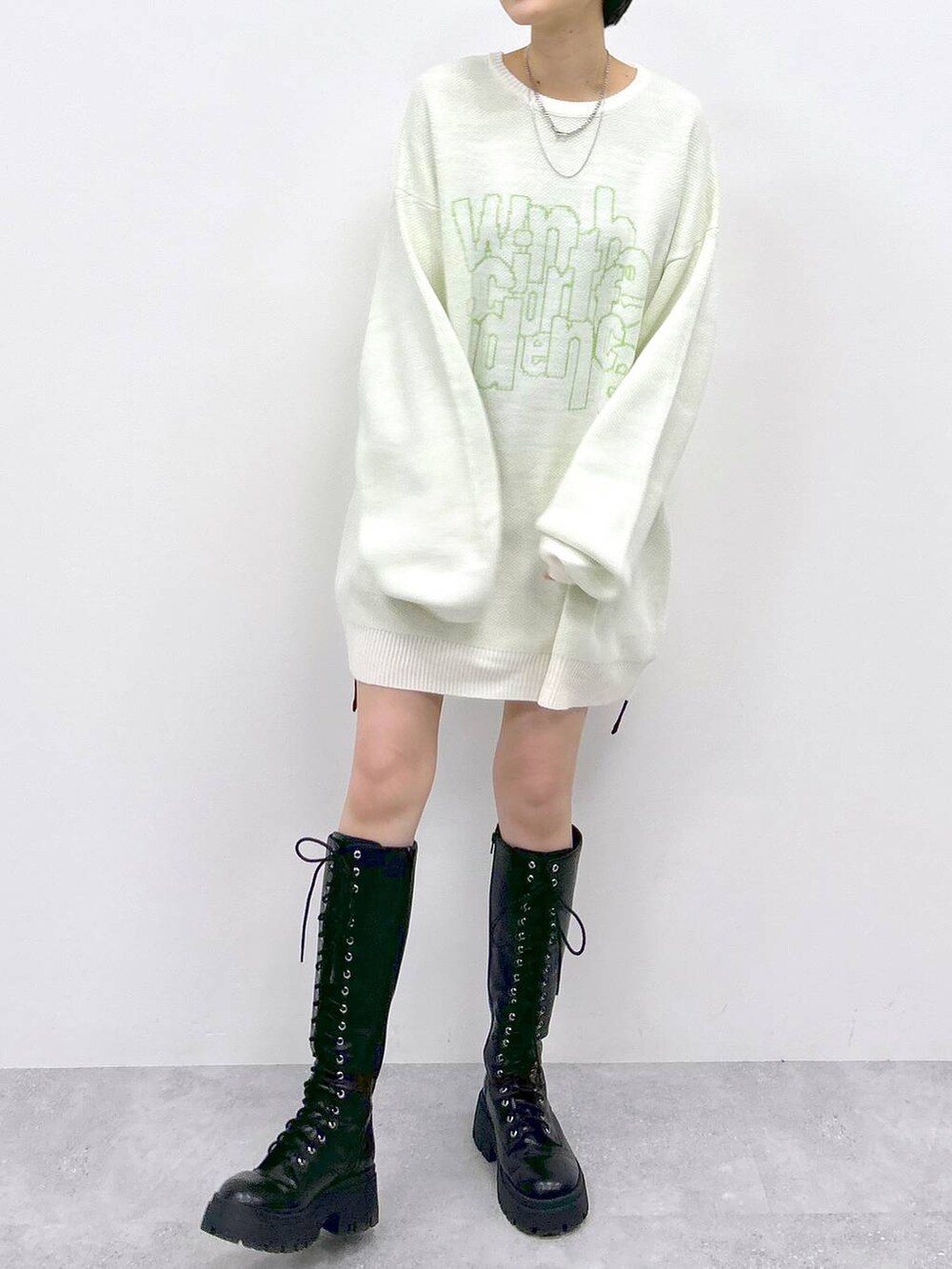 ブラック系のブーツ、ブラック系のスカート、ホワイト系のニット/セーターを着用したレディースの冬コーディネートの2枚目の写真