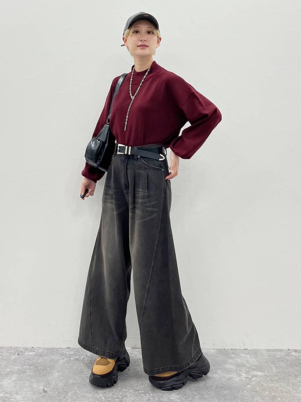 ブラック系のデニムパンツ、ブラウン系のブーツ、レッド系のニット/セーターを着用したレディースの秋コーディネートの4枚目の写真