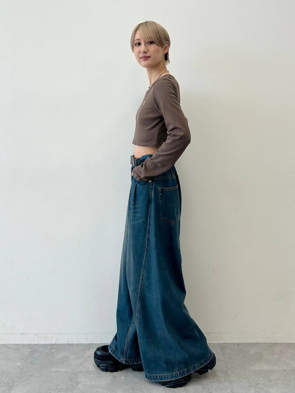 ブラック系のスニーカー、ブルー系のデニムパンツ、ブラウン系のTシャツ/カットソーを着用したレディースの春コーディネートの2枚目の写真