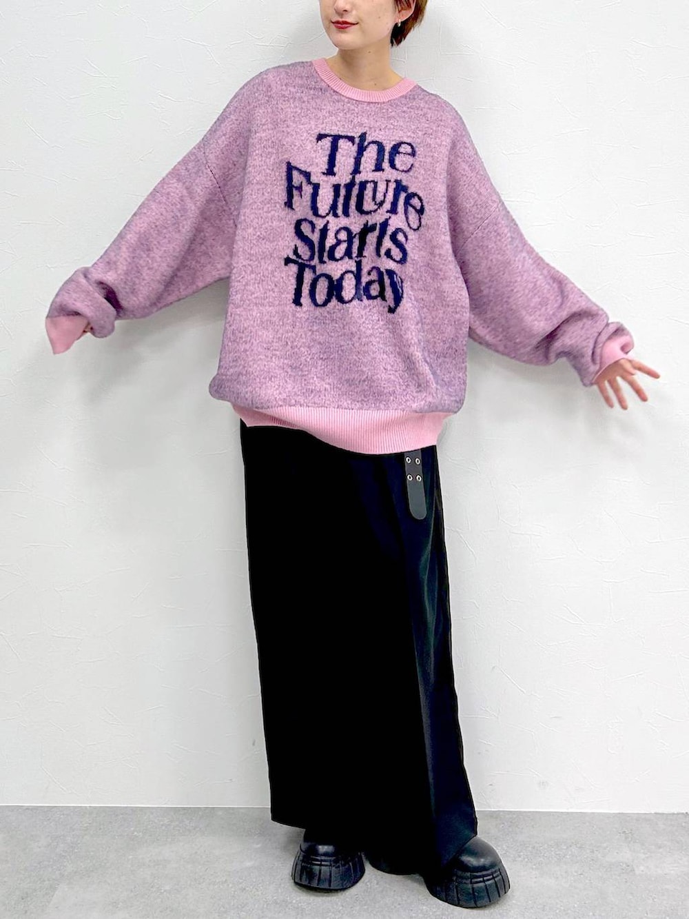 ピンク系のニット/セーター、ブラック系のブーツ、ブラック系のスラックスを着用したレディースの冬コーディネートの2枚目の写真