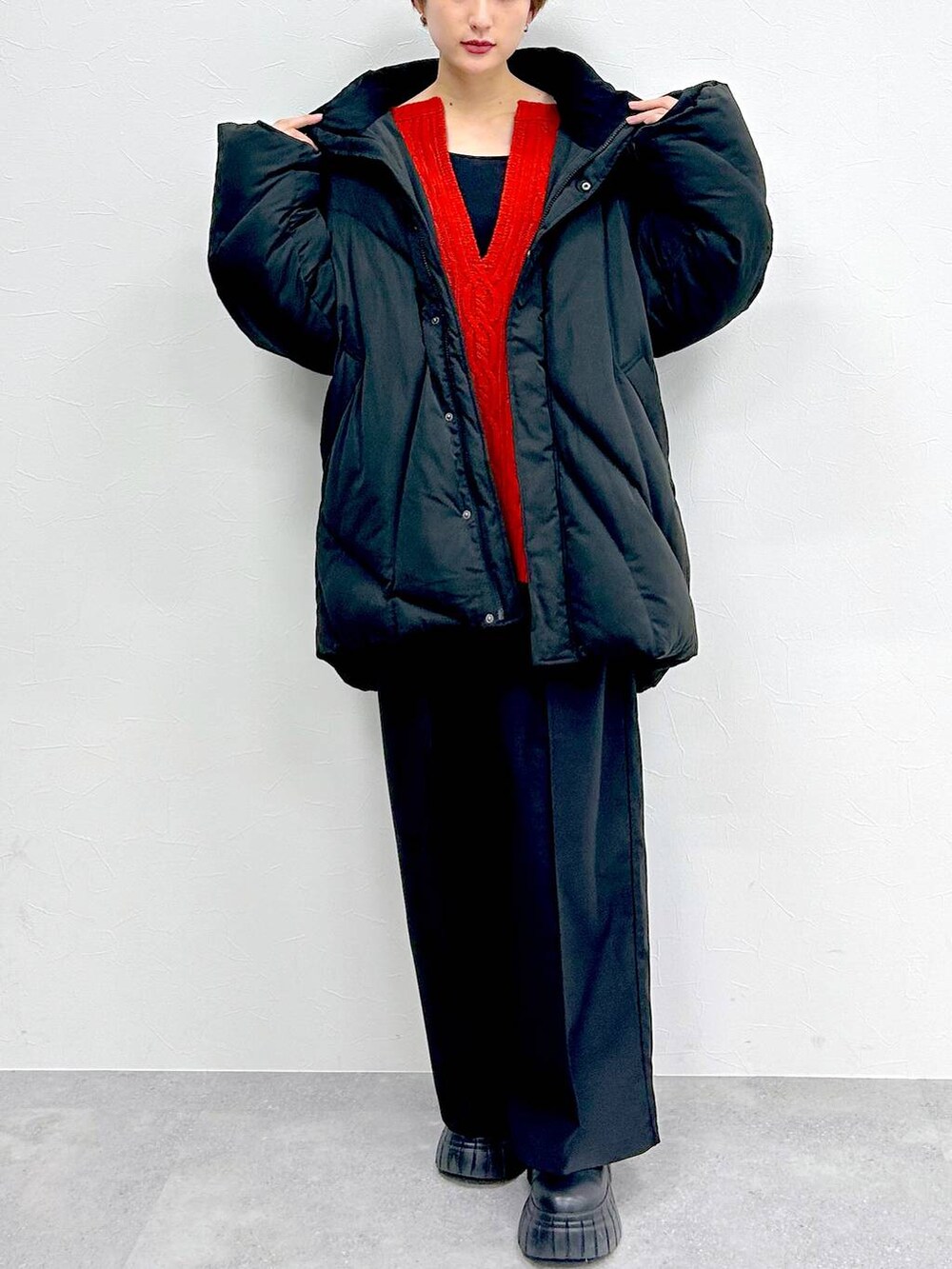 ブラック系のブルゾン、レッド系のニット/セーター、ブラック系のスラックスを着用したレディースの冬コーディネートの2枚目の写真