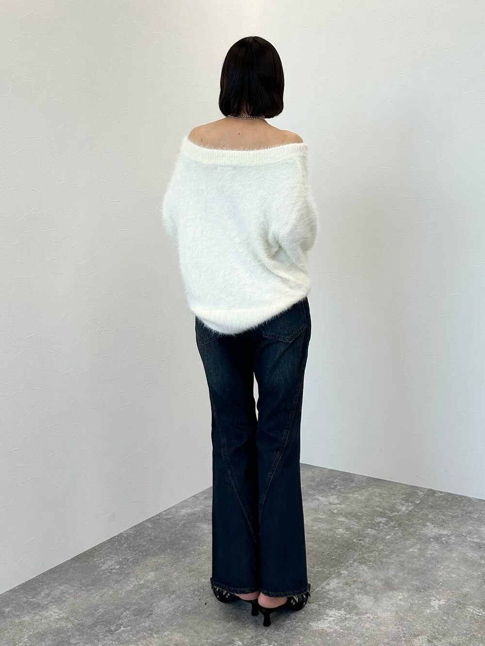 ブルー系のデニムパンツ、ブラック系のパンプス、ホワイト系のニット/セーターを着用したレディースの秋コーディネートの5枚目の写真