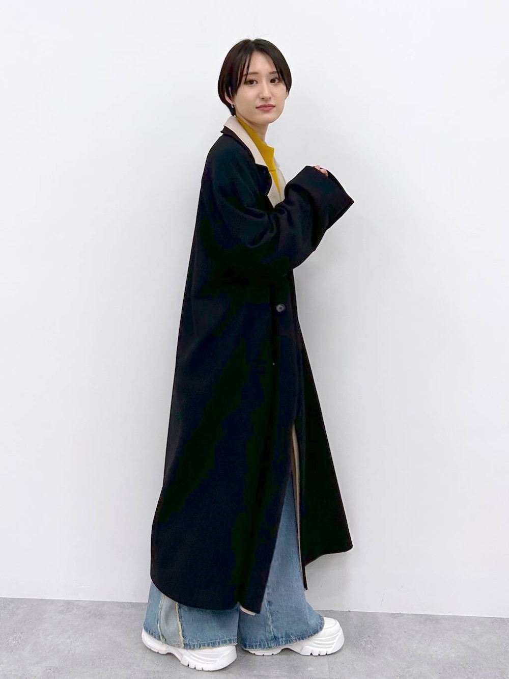 イエロー系のニット/セーター、ブルー系のデニムパンツ、ブラック系のその他アウターを着用したレディースの秋コーディネートの5枚目の写真