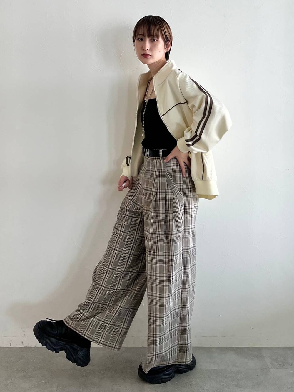 ブラック系のスニーカー、ベージュ系のスラックス、ホワイト系のジャージを着用したレディースの秋コーディネートの4枚目の写真