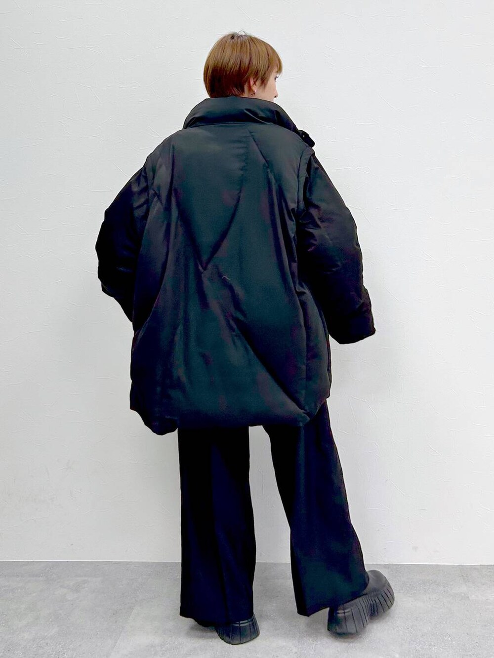 ブラック系のブルゾン、レッド系のニット/セーター、ブラック系のスラックスを着用したレディースの冬コーディネートの7枚目の写真