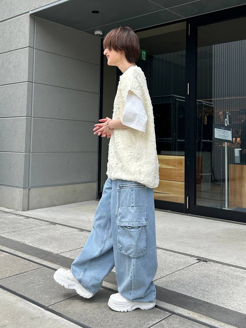 ホワイト系のベスト、ホワイト系のTシャツ/カットソー、ブルー系のデニムパンツを着用したレディースの夏コーディネートの3枚目の写真