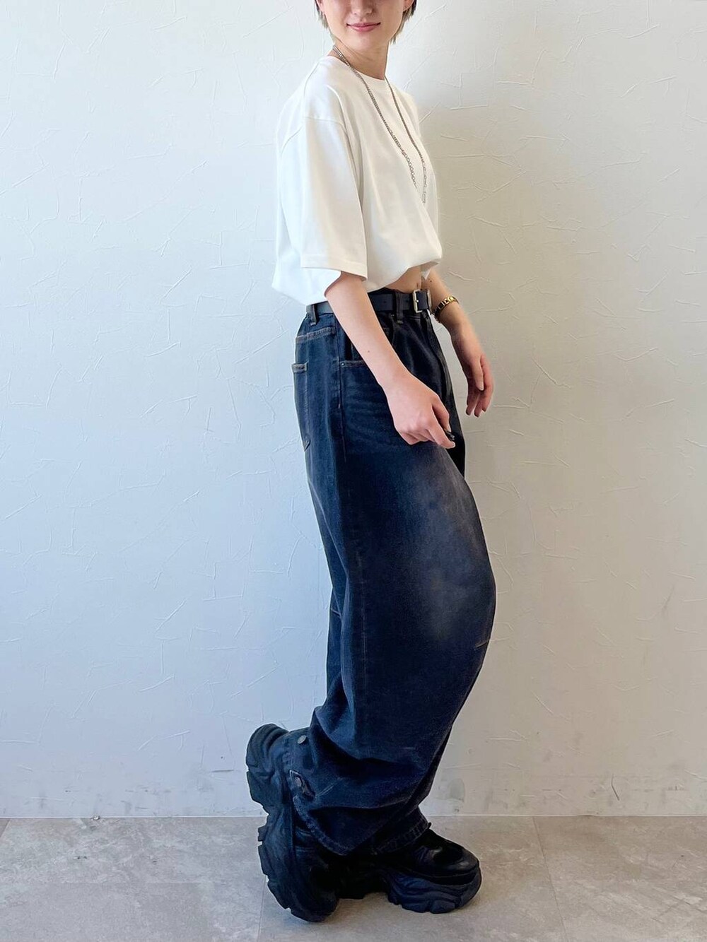 ブラック系のスニーカー、ブラック系のデニムパンツ、ホワイト系のTシャツ/カットソーを着用したレディースの春コーディネートの6枚目の写真