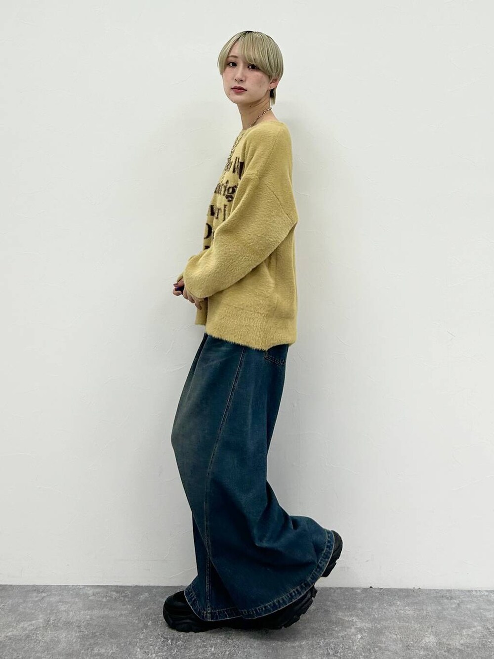 ブラック系のスニーカー、ブルー系のデニムパンツ、イエロー系のニット/セーターを着用したレディースの春コーディネートの4枚目の写真