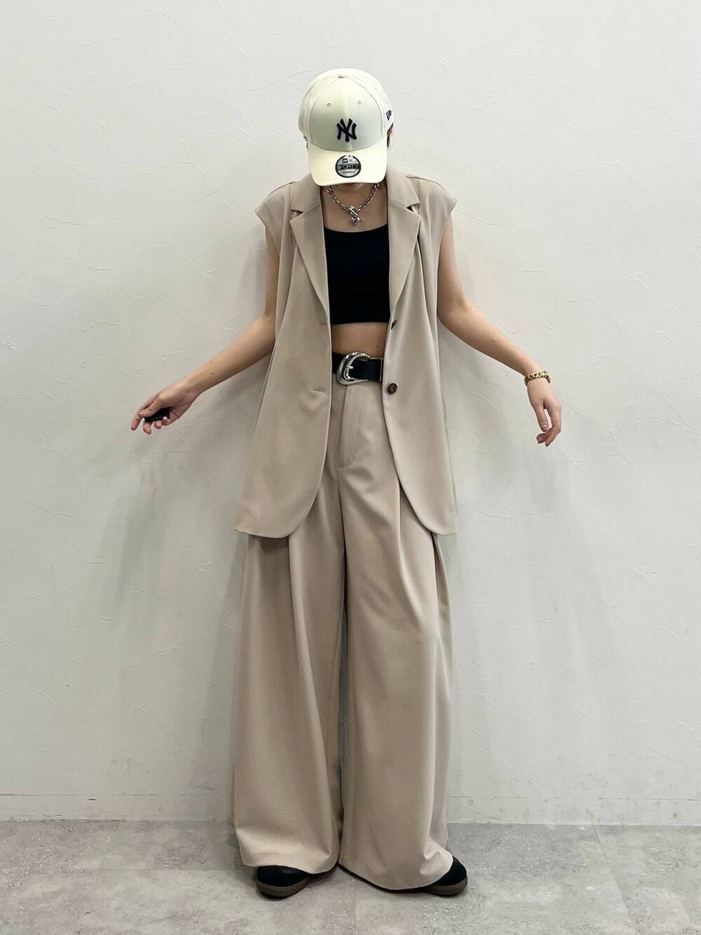 ブラック系のキャミソール、ベージュ系のスラックス、ブラック系のスニーカーを着用したレディースの春コーディネートの2枚目の写真