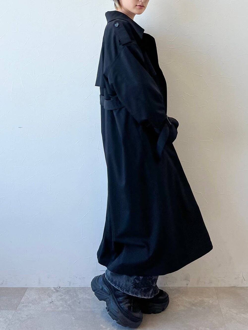 ブラック系のスニーカー、ブラック系のトレンチコート、ブラック系のデニムパンツを着用したレディースの春コーディネートの5枚目の写真