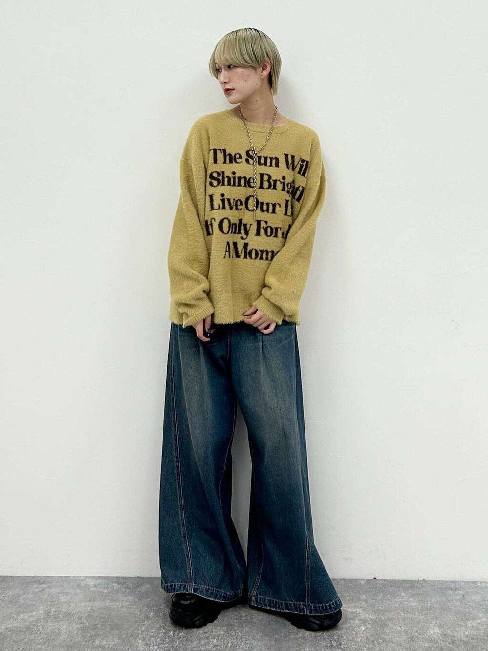 ブラック系のスニーカー、ブルー系のデニムパンツ、イエロー系のニット/セーターを着用したレディースの春コーディネートの2枚目の写真