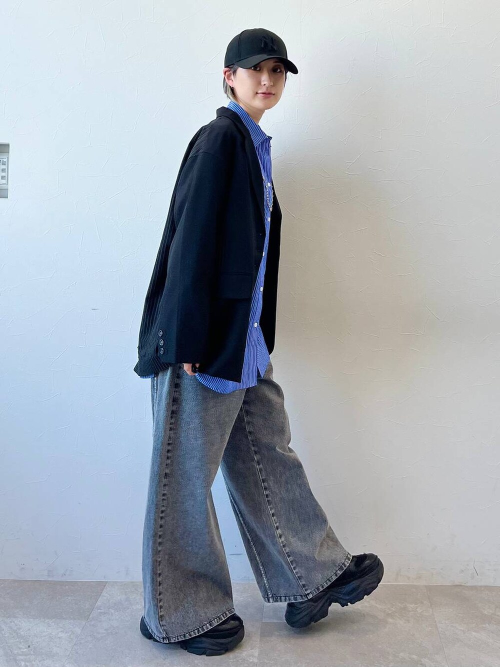 ブラック系のスニーカー、ブラック系のテーラードジャケット、ブラック系のデニムパンツを着用したレディースの春コーディネートの4枚目の写真