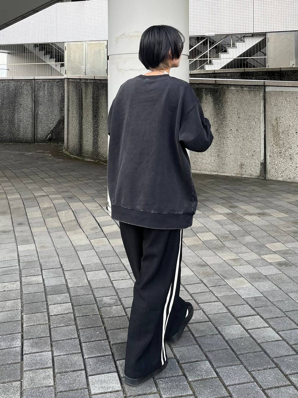 グレー系のスウェット、ブラック系のスラックス、ベージュ系のネックレスを着用したレディースの春コーディネートの6枚目の写真