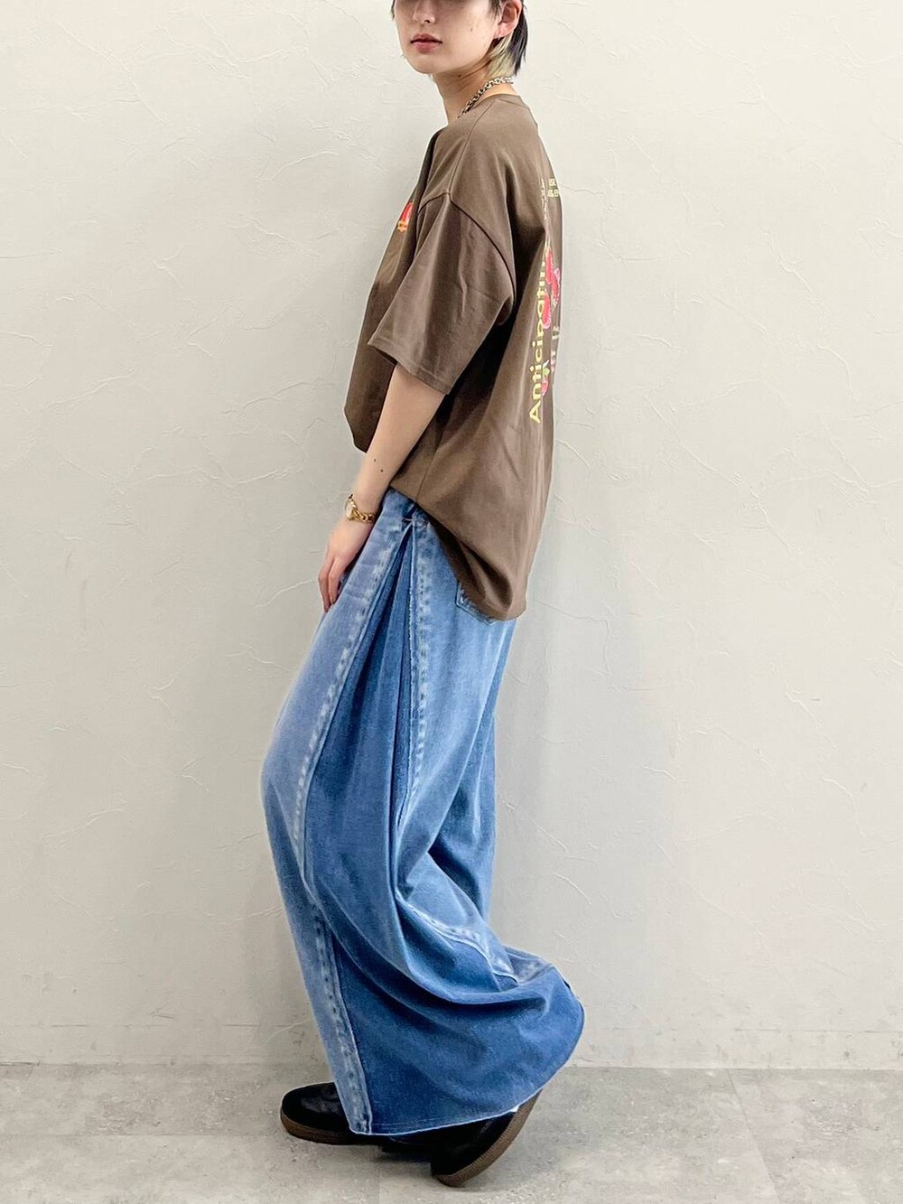 ブルー系のデニムパンツ、ブラック系のスニーカー、ブラウン系のTシャツ/カットソーを着用したレディースの春コーディネートの6枚目の写真