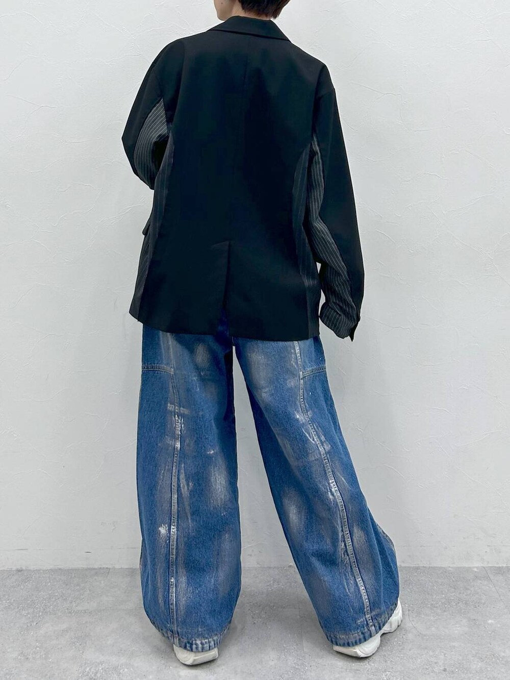 ブラック系のテーラードジャケット、ブルー系のデニムパンツ、シルバー系のネックレスを着用したレディースの春コーディネートの6枚目の写真