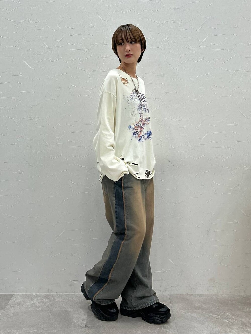 ブラック系のスニーカー、ホワイト系のTシャツ/カットソー、ブルー系のデニムパンツを着用したレディースの秋コーディネートの4枚目の写真