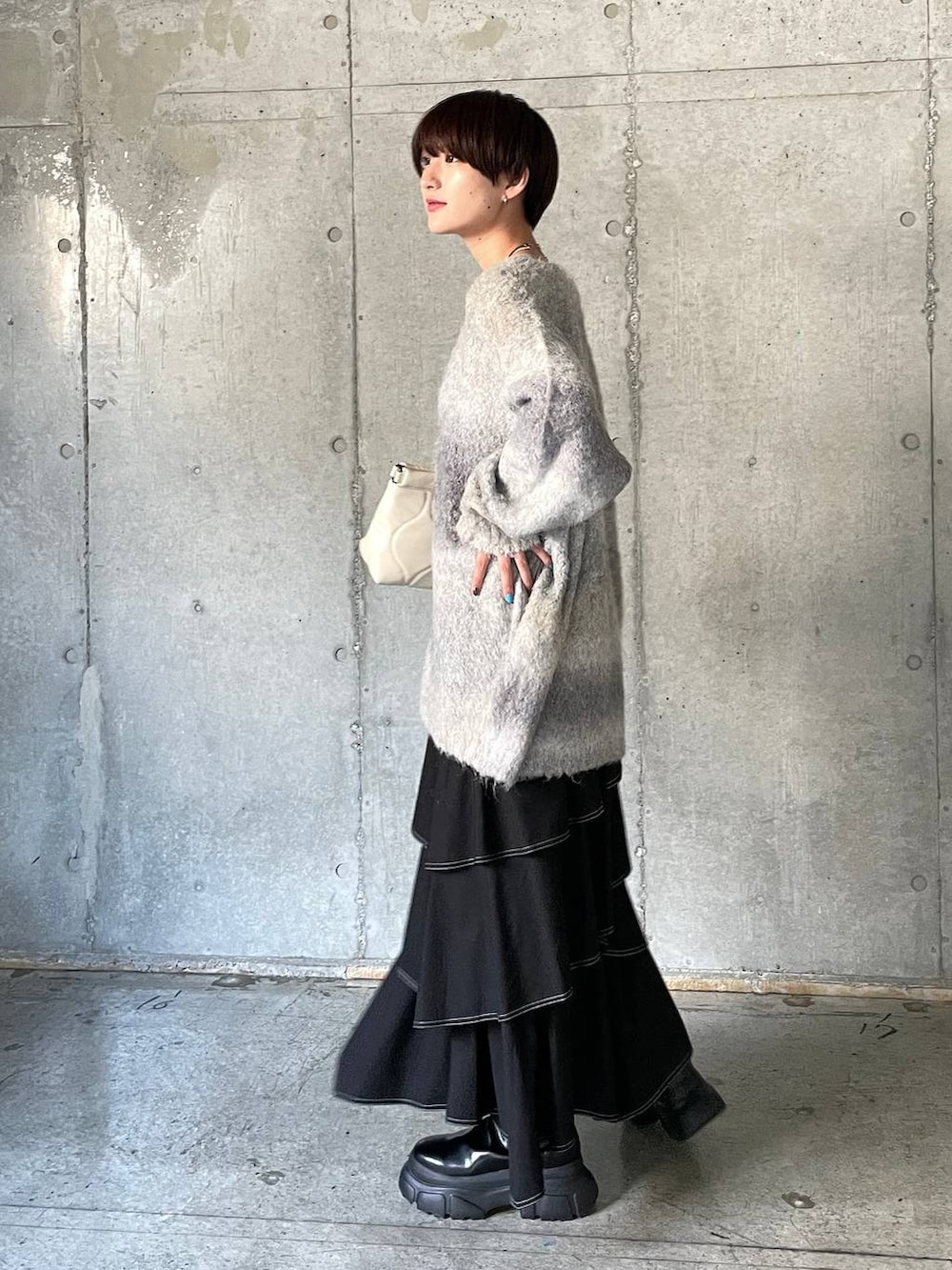 ホワイト系のキャミソール、ブラック系のブーツ、ホワイト系のクラッチバッグを着用したレディースの冬コーディネートの8枚目の写真