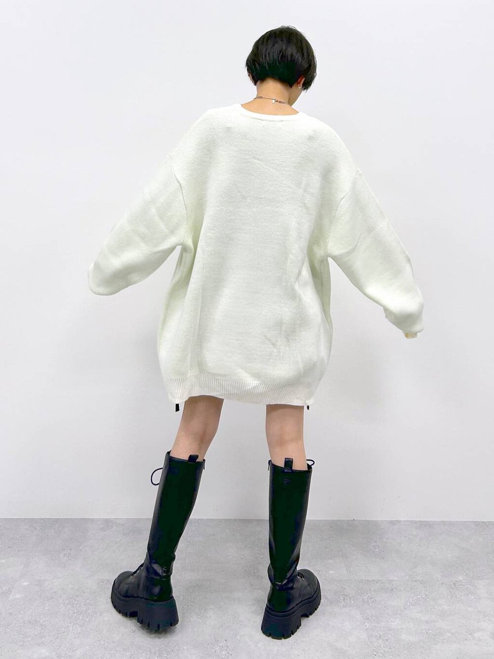 ブラック系のブーツ、ブラック系のスカート、ホワイト系のニット/セーターを着用したレディースの冬コーディネートの5枚目の写真