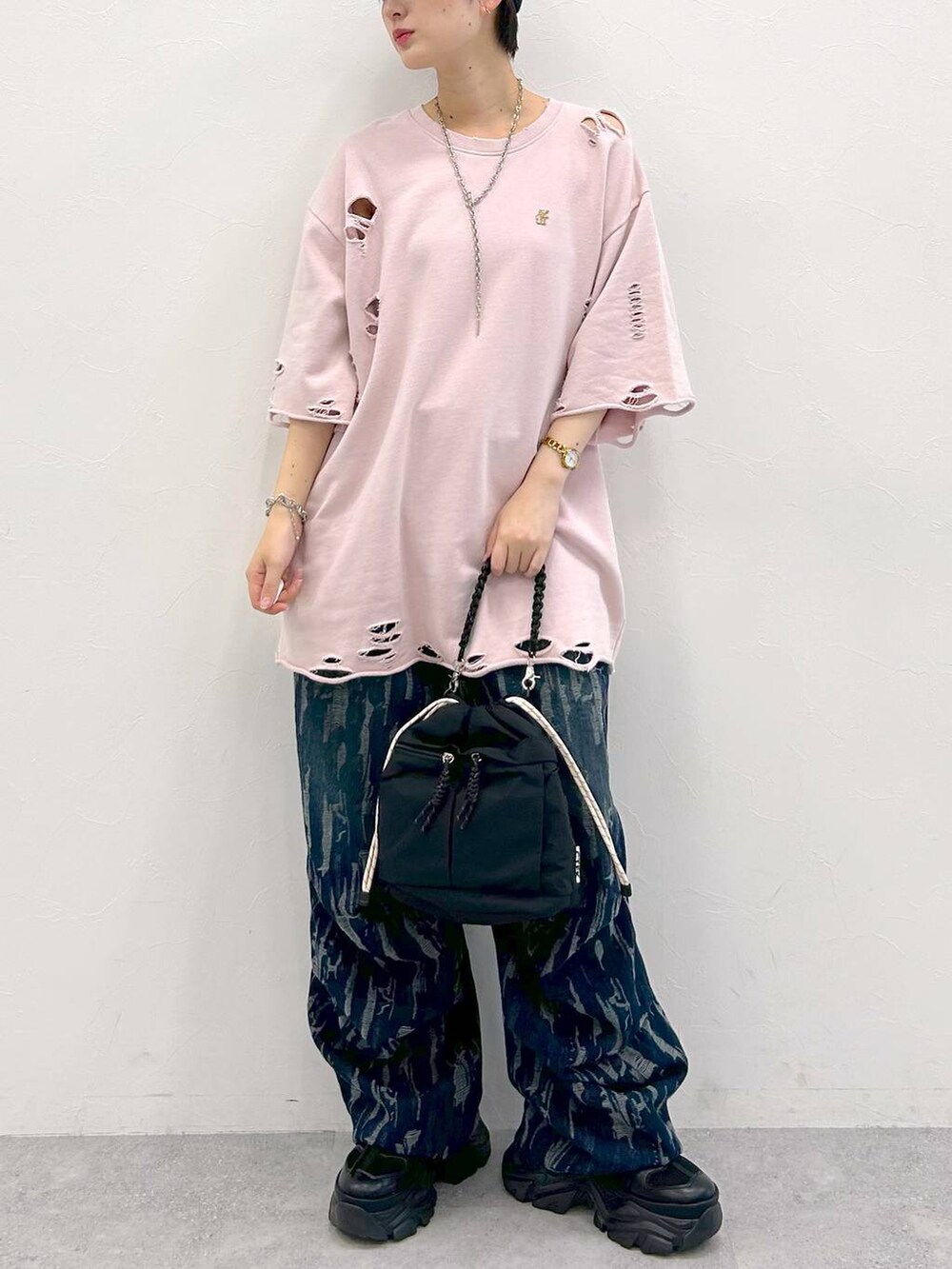 ブラック系のスニーカー、ブラック系のショルダーバッグ、ピンク系のTシャツ/カットソーを着用したレディースの夏コーディネートの3枚目の写真