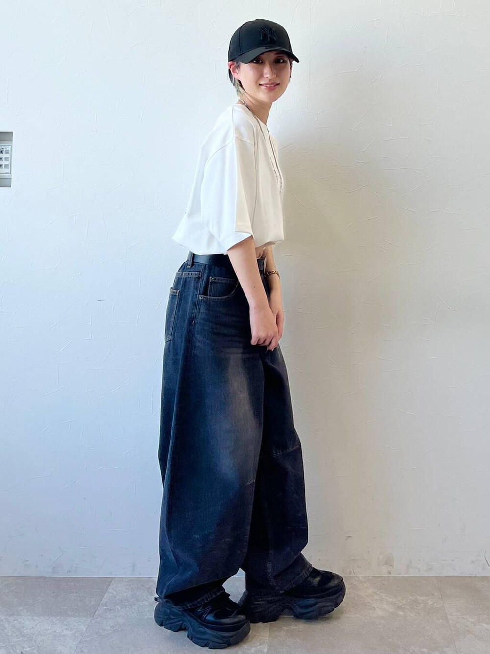 ブラック系のスニーカー、ブラック系のデニムパンツ、ホワイト系のTシャツ/カットソーを着用したレディースの春コーディネートの5枚目の写真