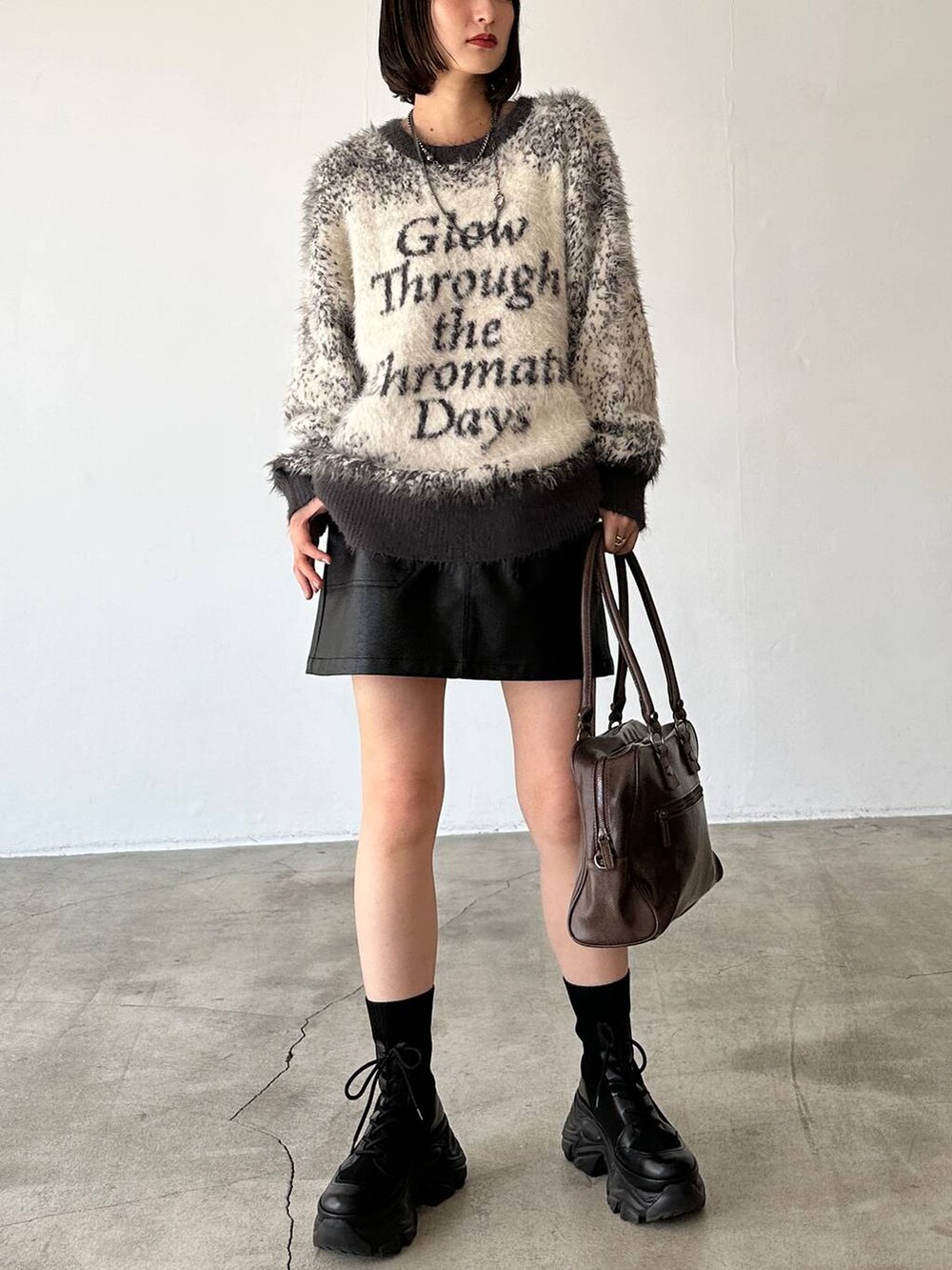 ブラック系のブーツ、ブラウン系のボストンバッグ、グレー系のニット/セーターを着用したレディースの秋コーディネートの4枚目の写真