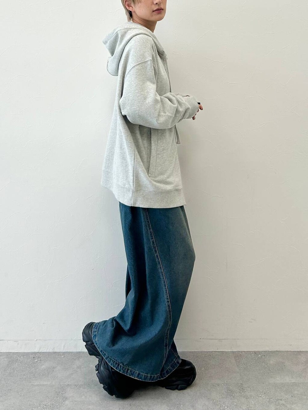 ブルー系のデニムパンツ、ブラック系のブーツ、グレー系のパーカーを着用したレディースの秋コーディネートの6枚目の写真