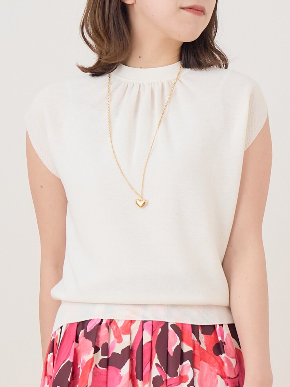 ピンク系のスカート、ホワイト系のニット/セーターを着用したレディースの春コーディネートの2枚目の写真