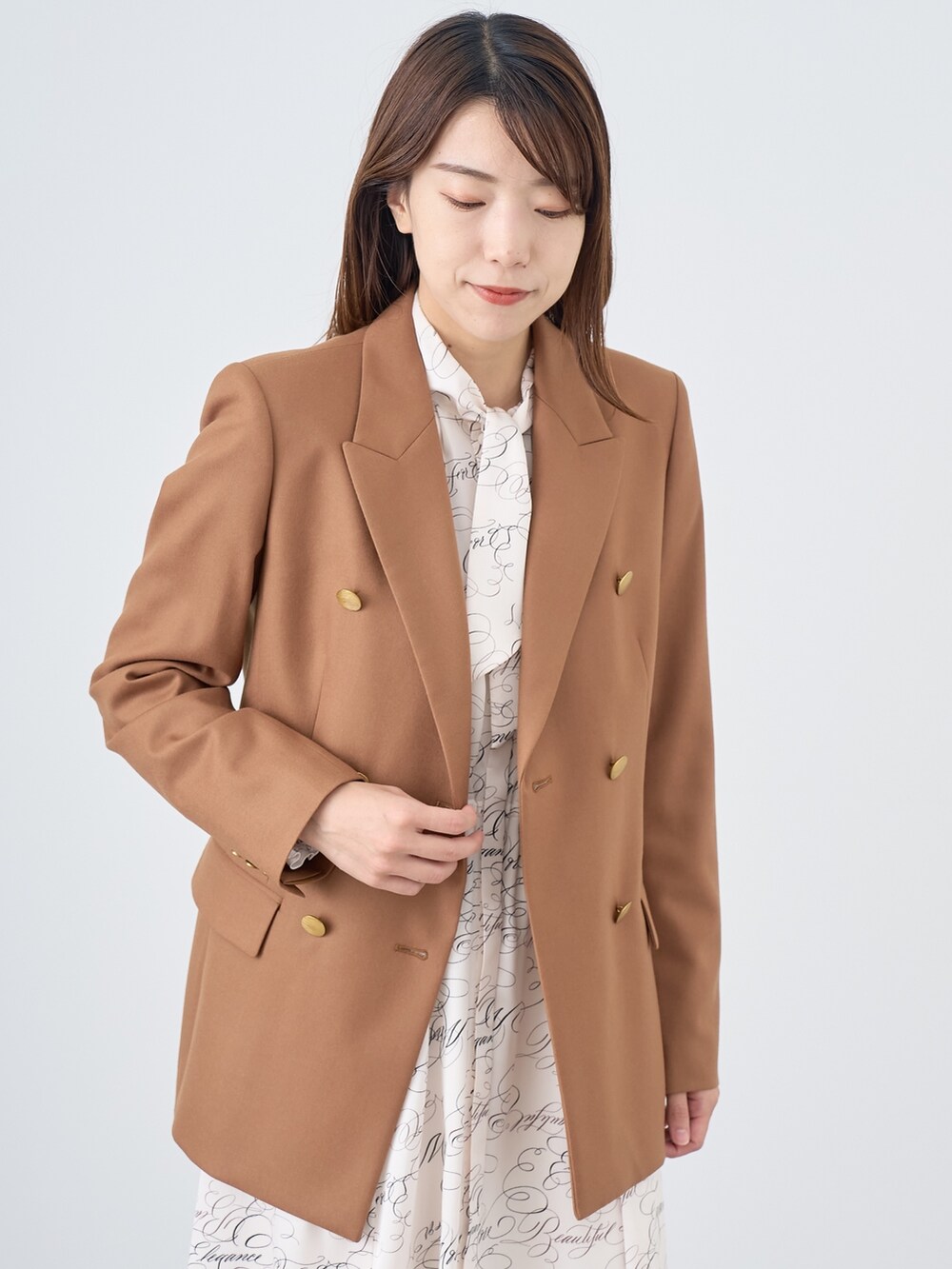 イエロー系のテーラードジャケット、ホワイト系のワンピースを着用したレディースの秋コーディネートの3枚目の写真