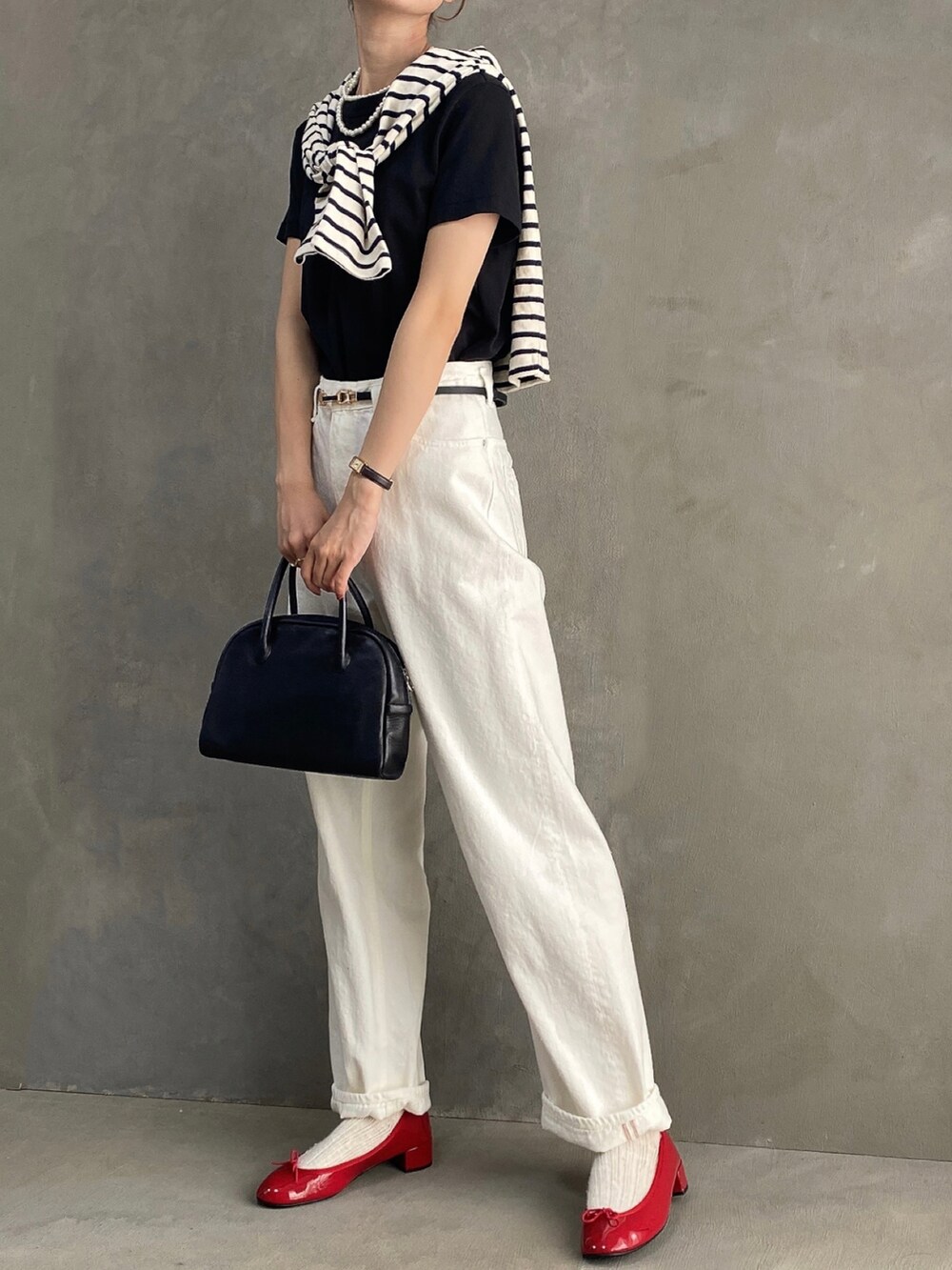 ブラック系のボストンバッグ、レッド系のパンプス、ホワイト系のデニムパンツを着用したレディースの夏コーディネートの3枚目の写真