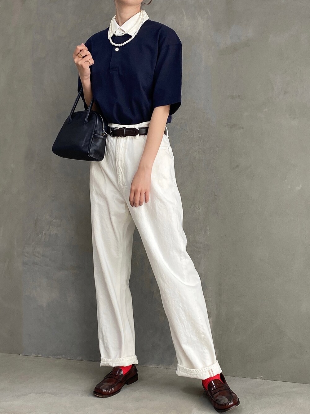 ブルー系のポロシャツ、ブラック系のボストンバッグ、ホワイト系のデニムパンツを着用したレディースの春コーディネートの2枚目の写真