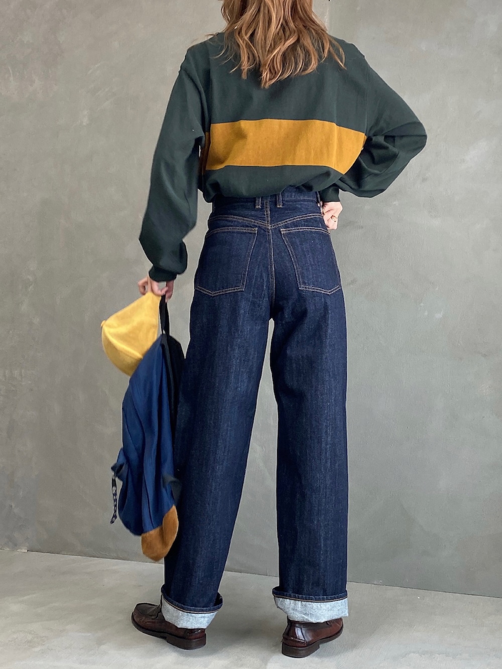 ブルー系のバックパック/リュック、グリーン系のTシャツ/カットソー、ブルー系のデニムパンツを着用したレディースの春コーディネートの2枚目の写真